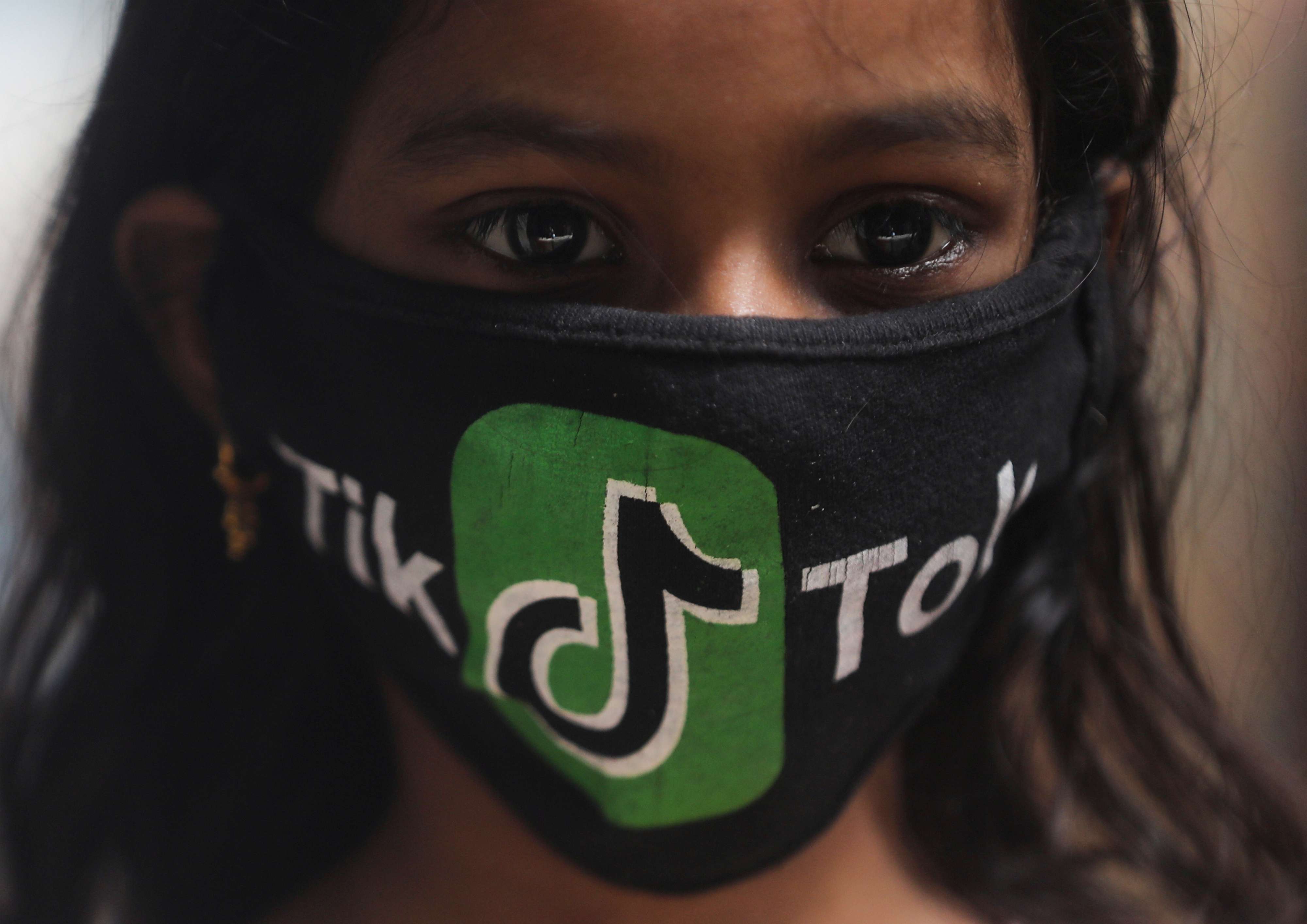 فتاة هندية ترتدي كمامة بشعار تطبيق تيك توك