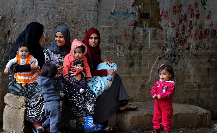 Syrian refugees women hold their children as they sit in Ouzai refugee compound, in the southern port city of Sidon, Lebanon. 