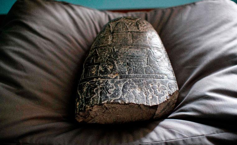 A Babylonian cuneiform kudurru (boundary stone) which was looted from Iraq sits on a cushion at the British museum in London on March 19, 2019.