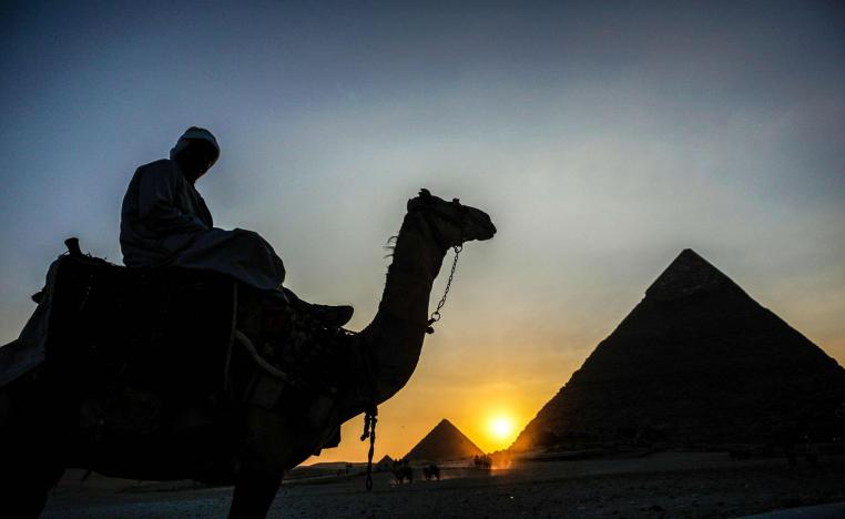 رجل يركب جملا بالقرب من الاهرامات في مصر