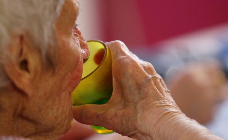 سيدة مسنة تشرب كأس ماء في إحدى دور الرعاية الصحية في فرنسا