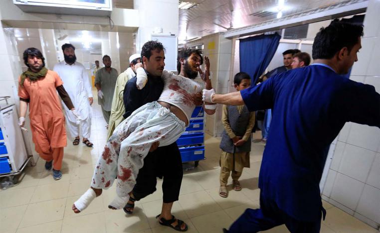 A man carries an injured person in a hospital after blasts, in Jalalabad
