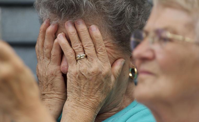 سيدة أميركية مسنة تضع يديها على رأسها خلال قداس دفن مسيحي