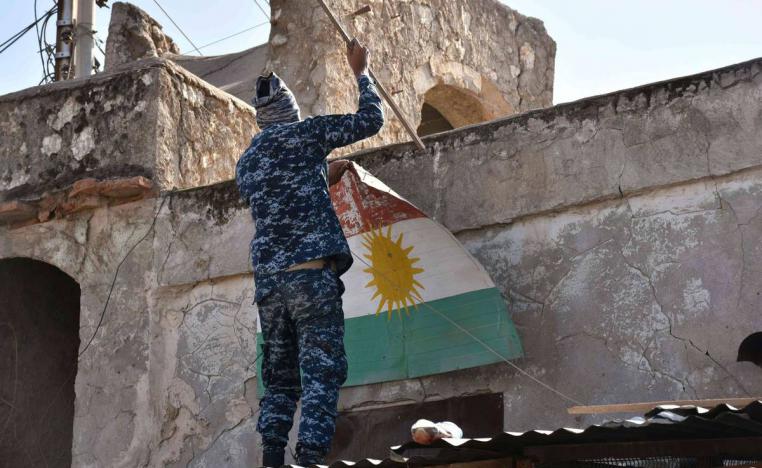 جندي عراقي يزيل علما كرديا من مبنى في كركوك