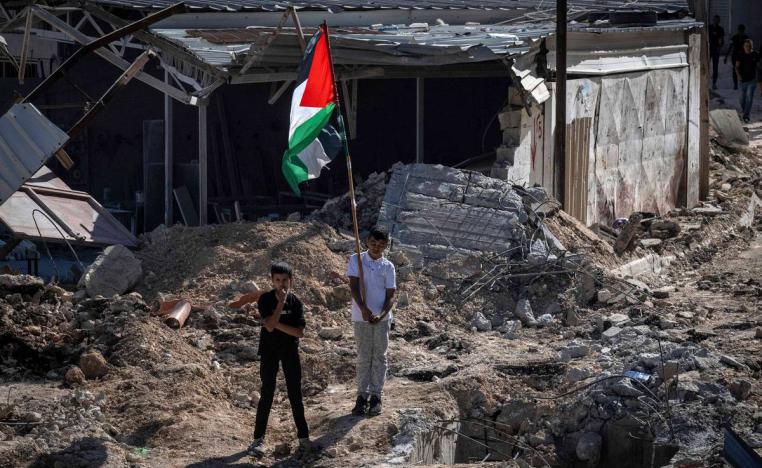 أطفال فلسطينيون يرفعون علما على أطلال مبنى مدمر في مخيم جنين في الضفة الغربية