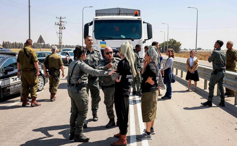 Israeli border guards talk to right-wing protesters blocking the road to Jordanian trucks carrying humanitarian aid supplies to Gaza