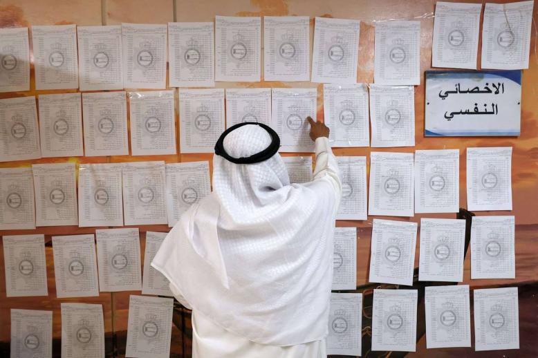 كويتي يدقق قوائم المرشحين في مركز انتخابي