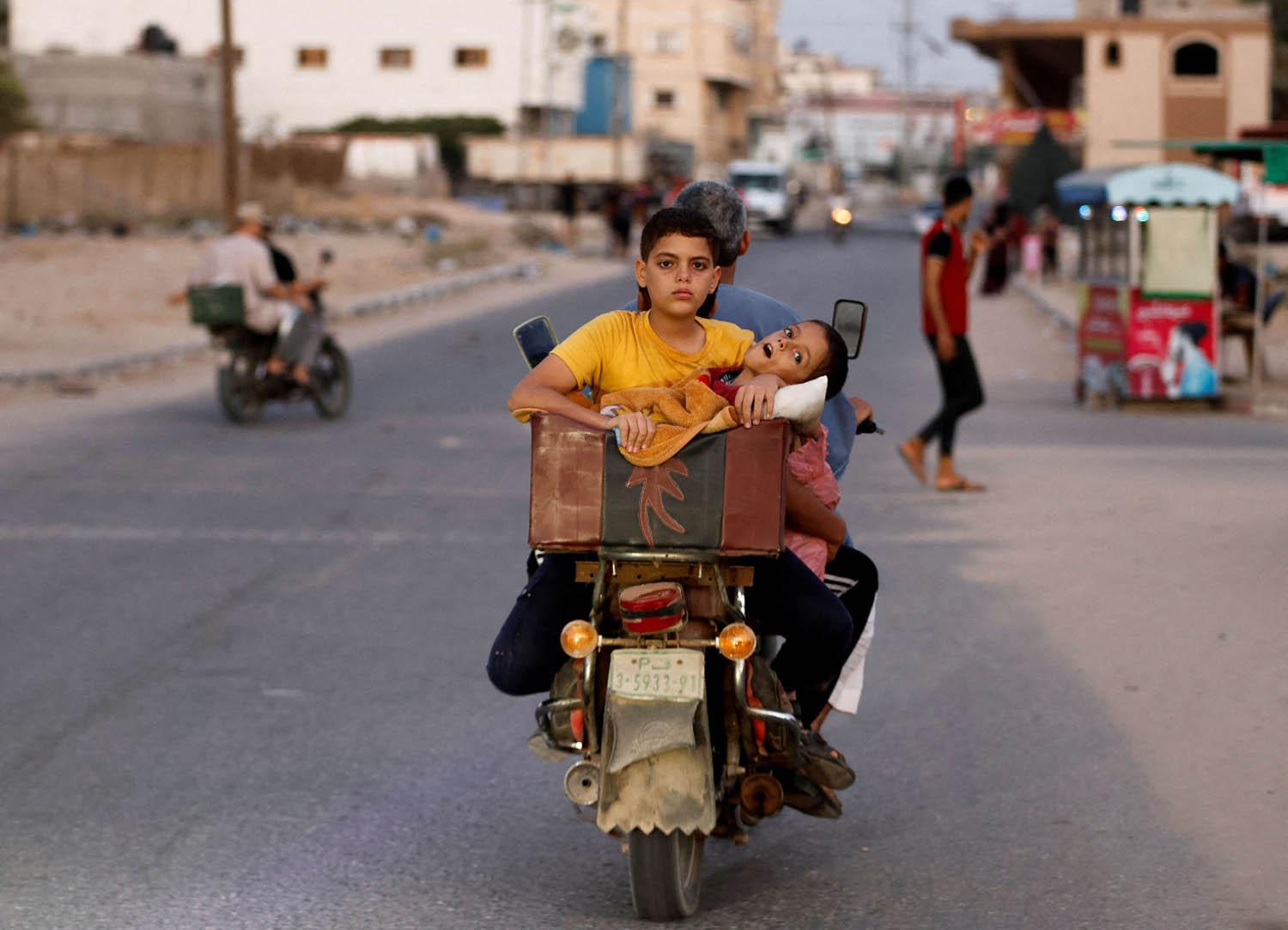 فلسطيني ينقل أولاده على دراجة نارية خلال قصف إسرائيلي على غزة