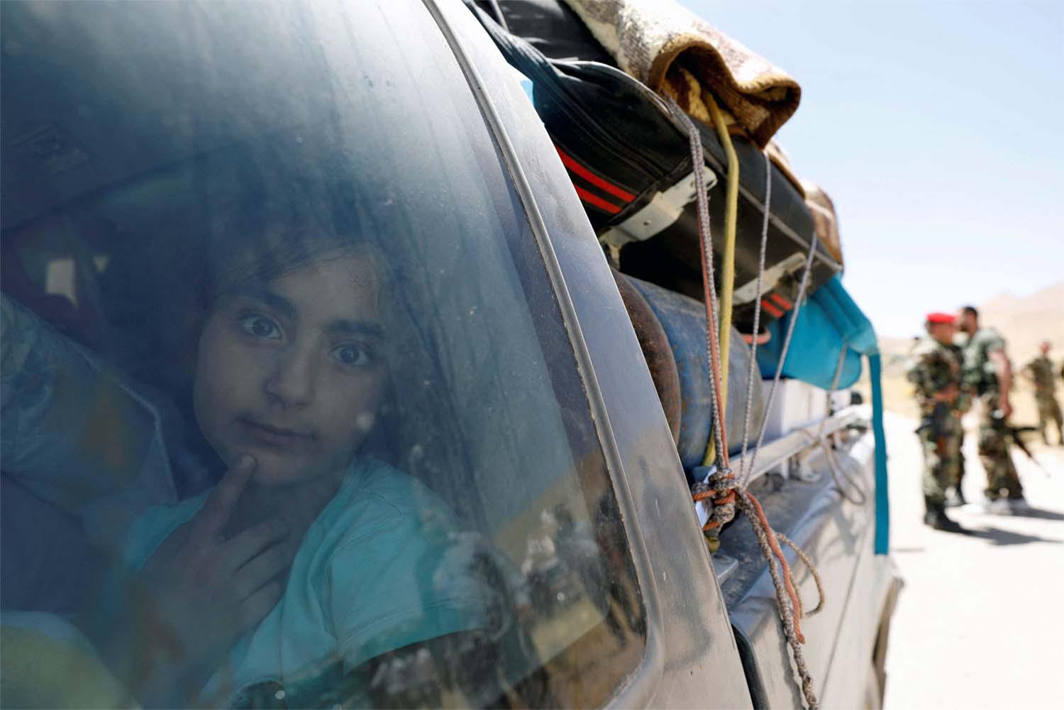 A Syrian refugee girl who left Lebanon looks through a window as she arrives in Qalamoun, Syria