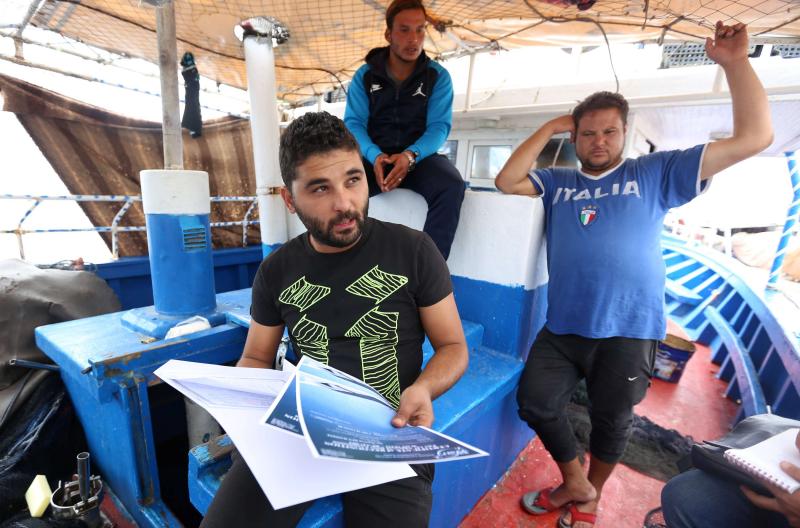 Young people show their diplomas as they discuss plans to make an illegal boat trip in Tunisia’s Port Monastir