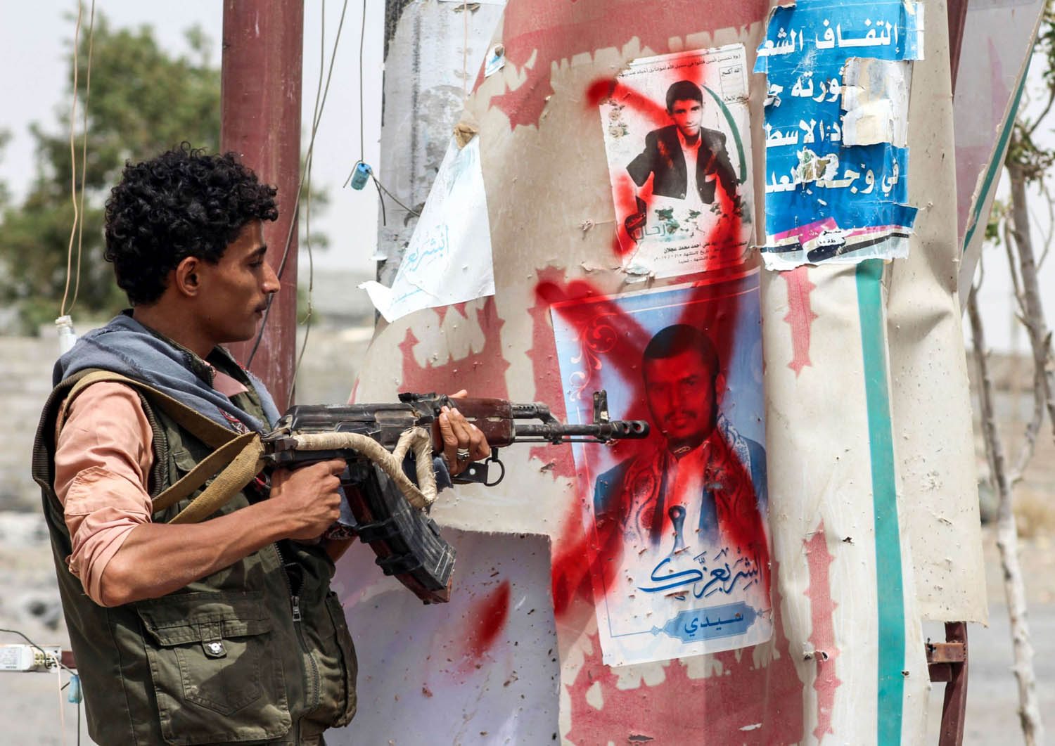 مقاتل يمني من المقاومة الشعبية يوجه بندقيته لصور للحوثي