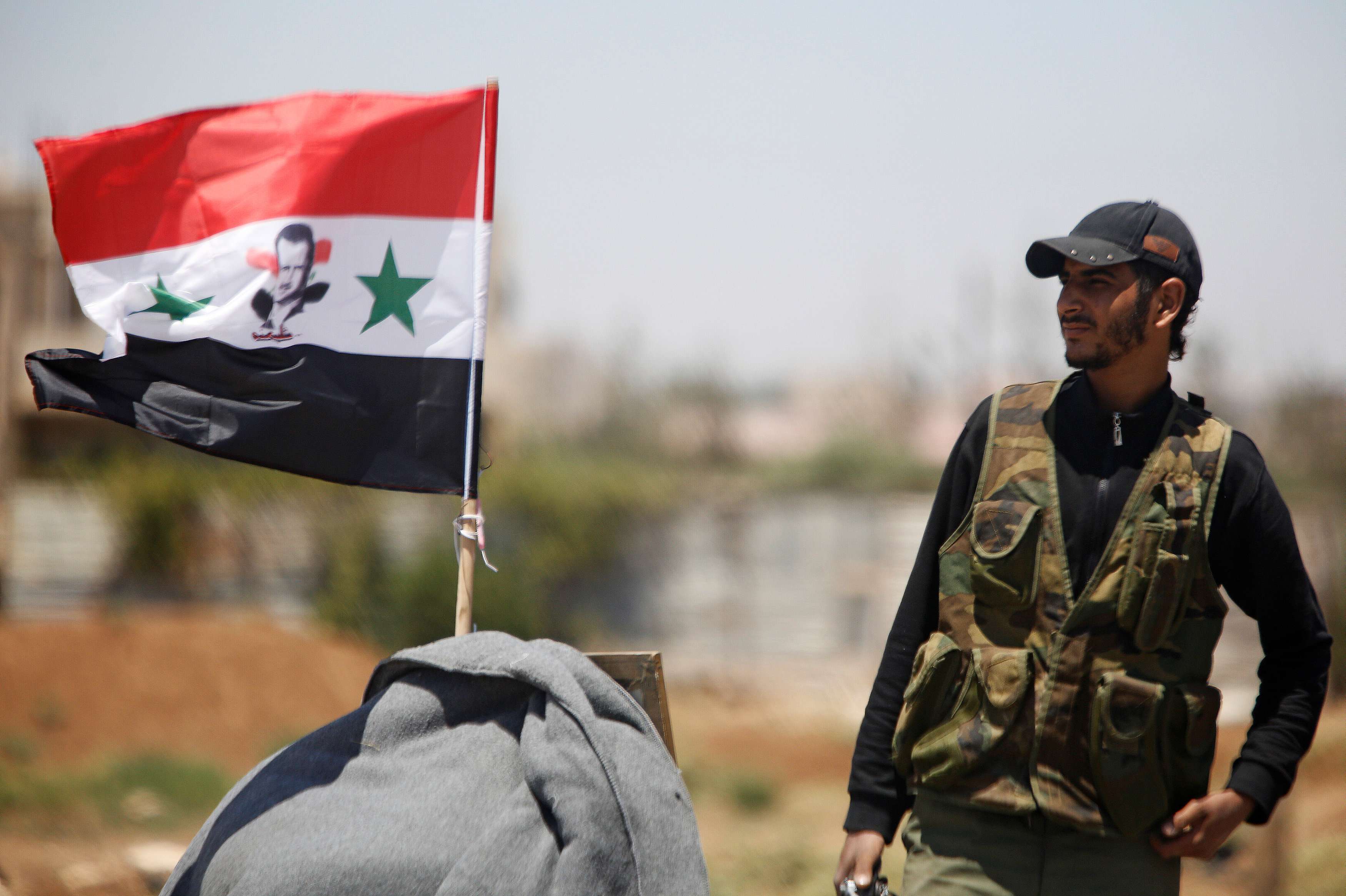 جندي سوري أمام علم االبلاد