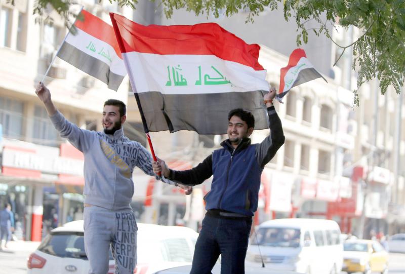 Iraqi men wave their national flags on the streets of Baghdad