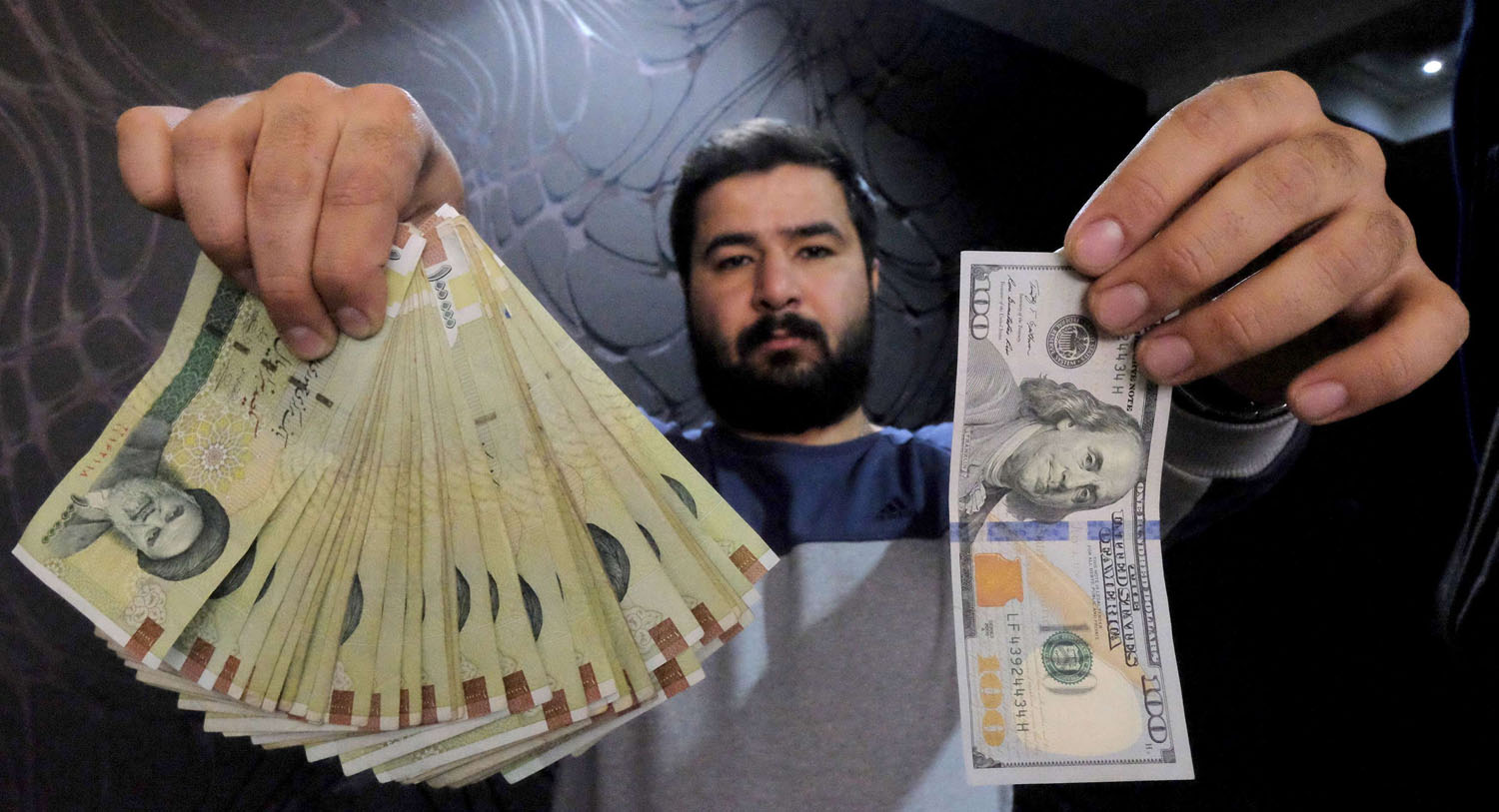 تاجر عملة في طهران يعرض الفرق بين قيمة الدولار وقيمة العملة الوطنية