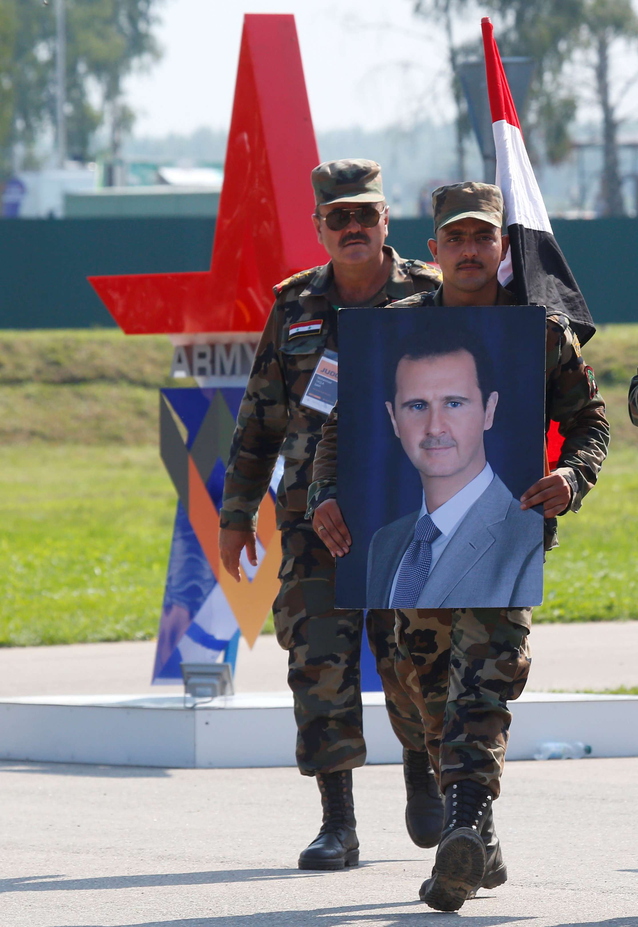 جندي سوري يحمل صورة الأسد
