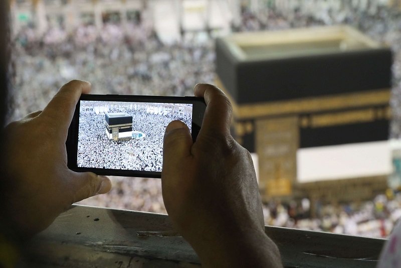 يد تمسك هاتفا ذكيا لتصوير الكعبة