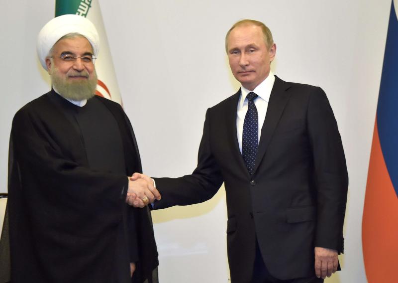 Russian President Vladimir Putin (R) shakes hands with Iranian leader Hassan Rohani