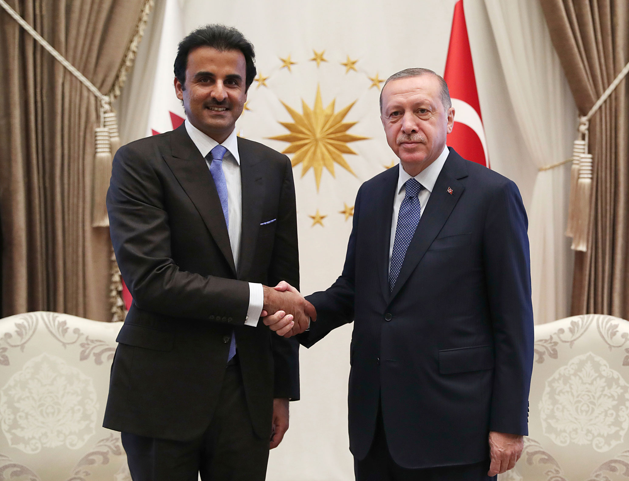 الرئيس التركي رجب طيب اردوغان يصافح ضيفه أمير قطر الشيخ تميم بن حمد ببرود