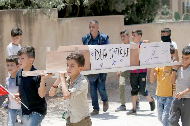 Palestinian children carry the fake coffin of the “deal of Trump” during a demonstration in Kfar Qaddum near Nablus