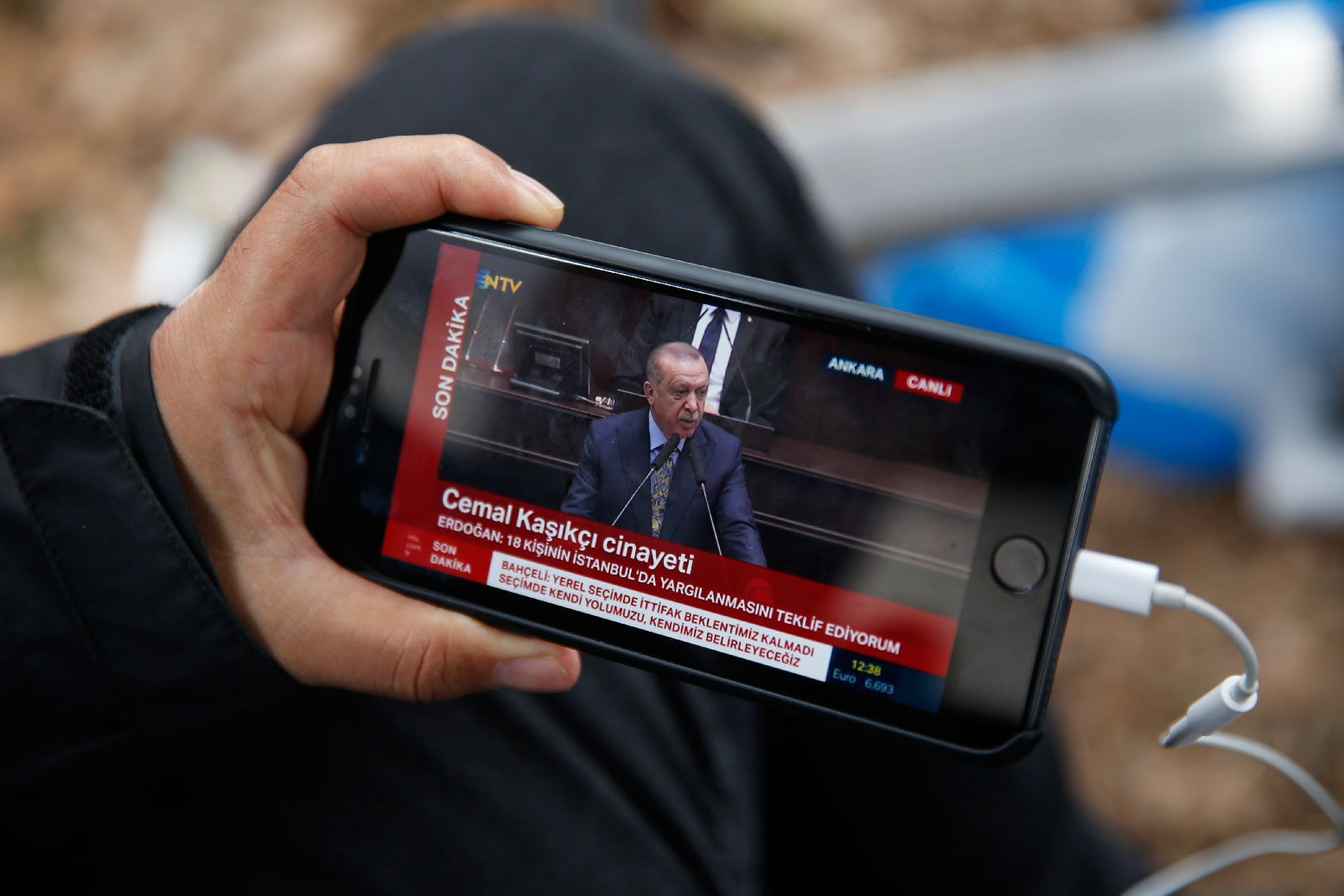 A journalist covering the killing of Saudi writer Jamal Khashoggi, watches a live transmission of Turkey's President Recep Tayyip Erdogan addressing members of his ruling Justice and Development Party (AKP), at the parliament in Ankara, Turkey, Tuesday, Oct. 23, 2018.