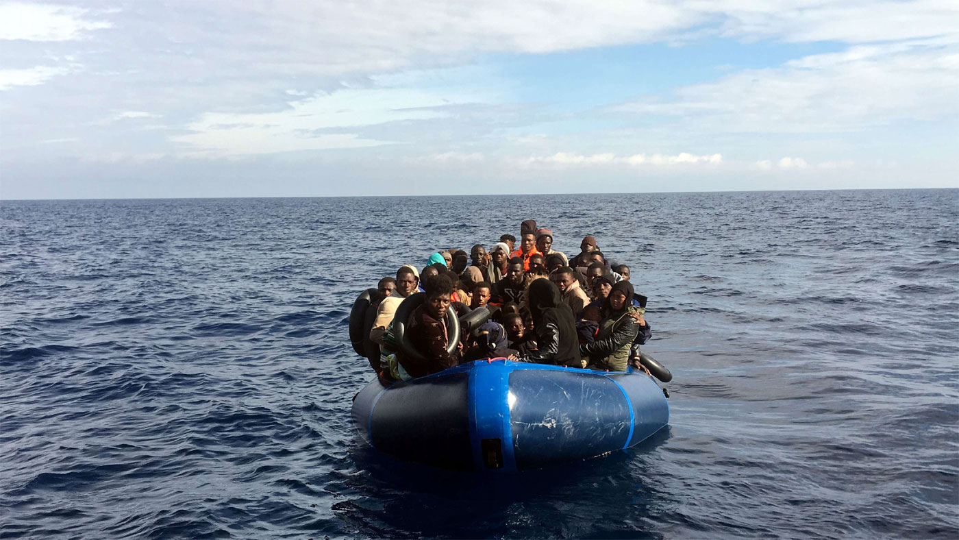 Migrants look on from a rubber boat before being rescued in the Mediterranean Sea 