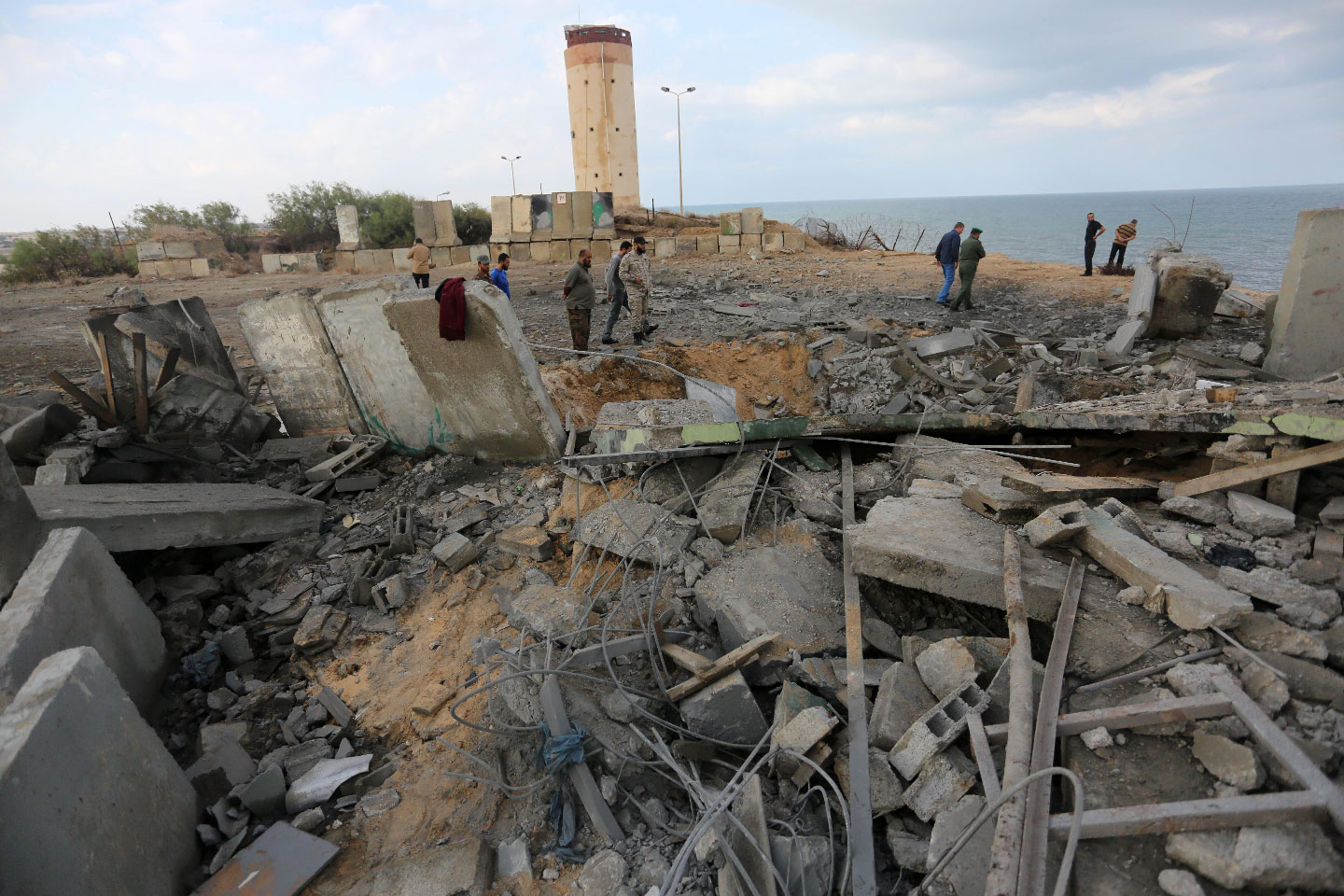 Palestinian men inspect the damage at a site targeted by an Israeli air strike.