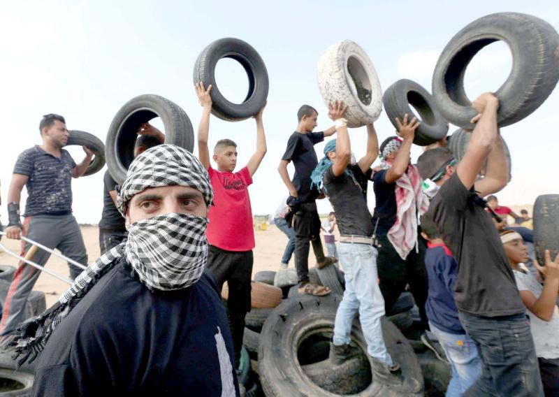 Palestinian demonstrators hold tyres during a protest at the border fence in southern Gaza, on October 19