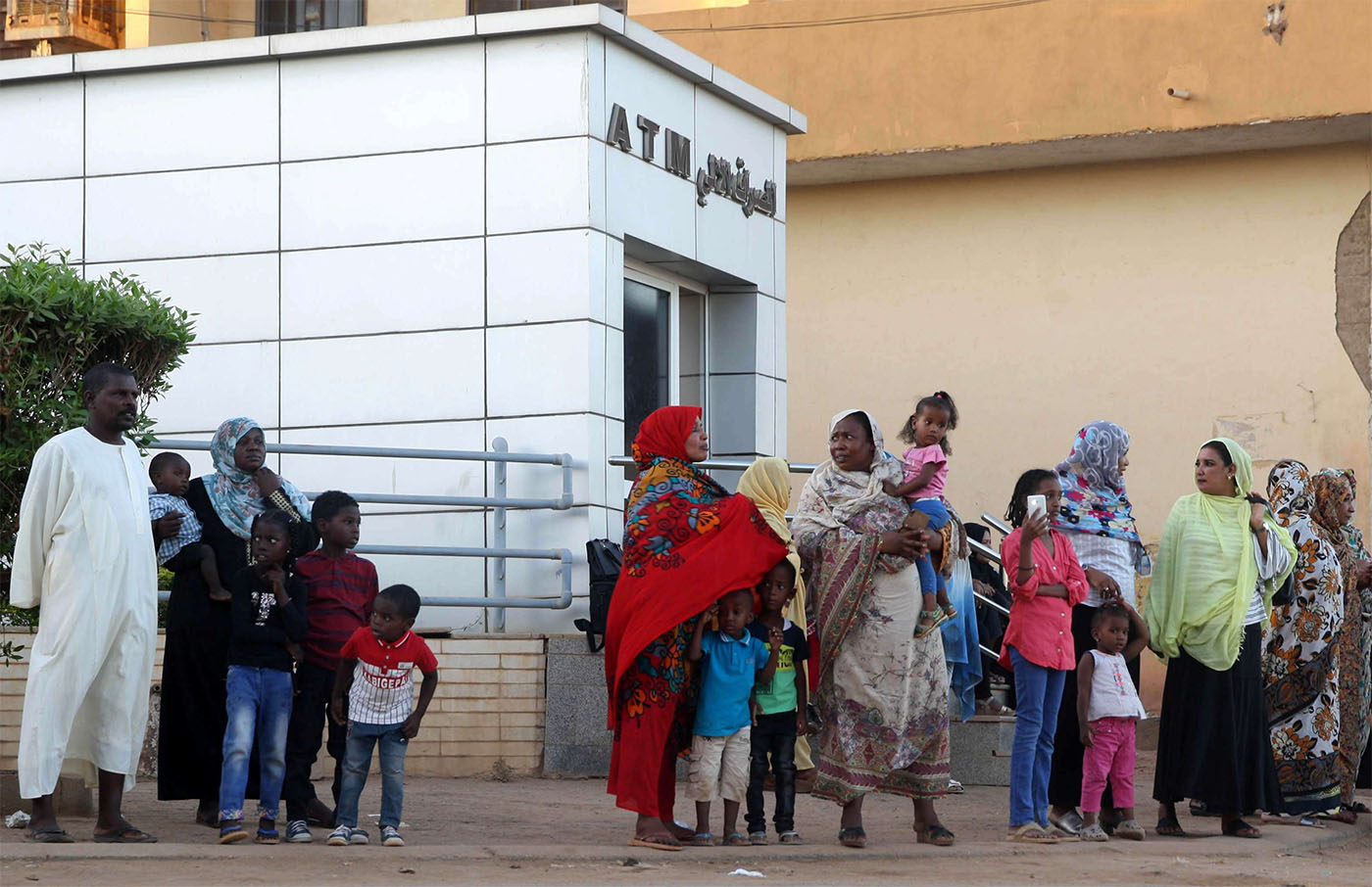 Residents stand outside an automated teller machine (ATM) in Khartoum