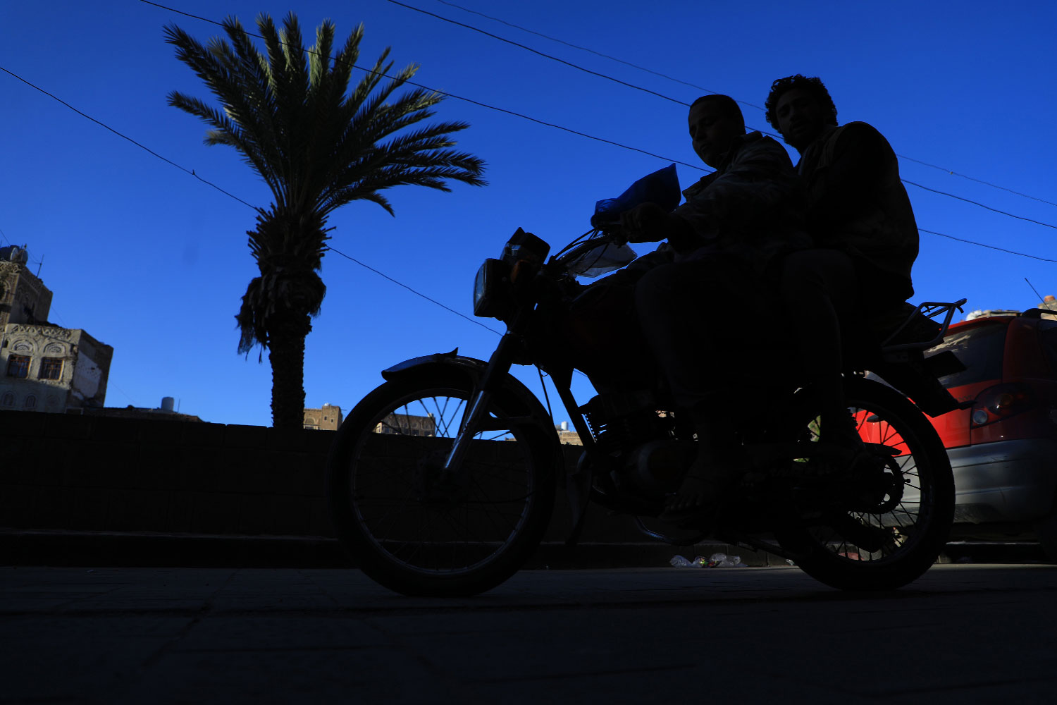 Yemenis ride a motorbike past historical buildings in the old quarter of the capital Sanaa on November 14, 2018.