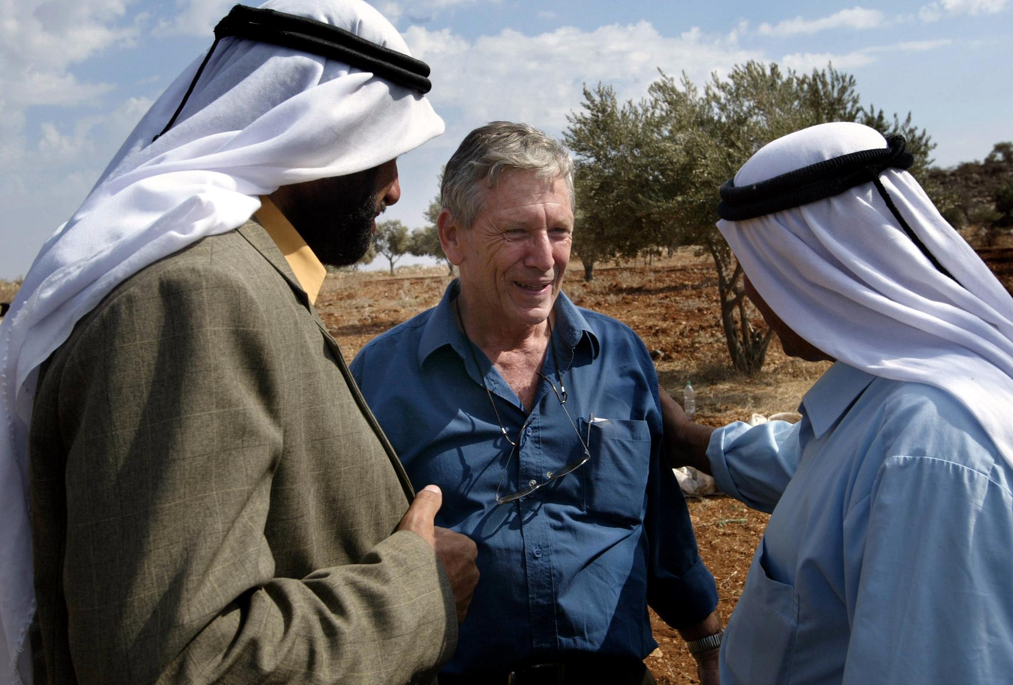 In this file photo taken on October 30, 2002 Israeli writer Amos Oz (C) talks with Palestinian men after picking olives in the West Bank village of Aqraba, south of Nablus.