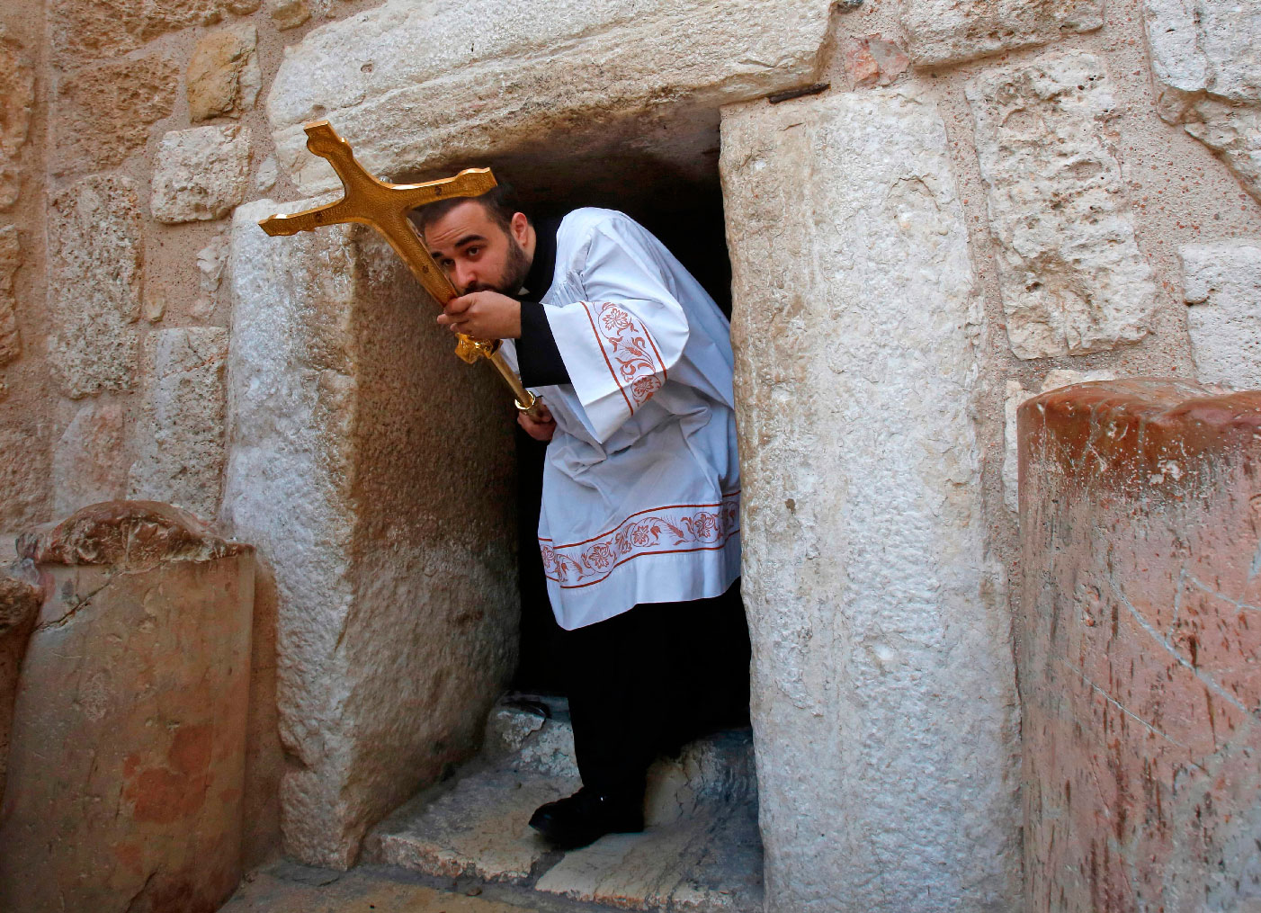 A Latin clergy carries a cross at the Church of the Nativity in the West Bank city of Bethlehem on December 24, 2018.