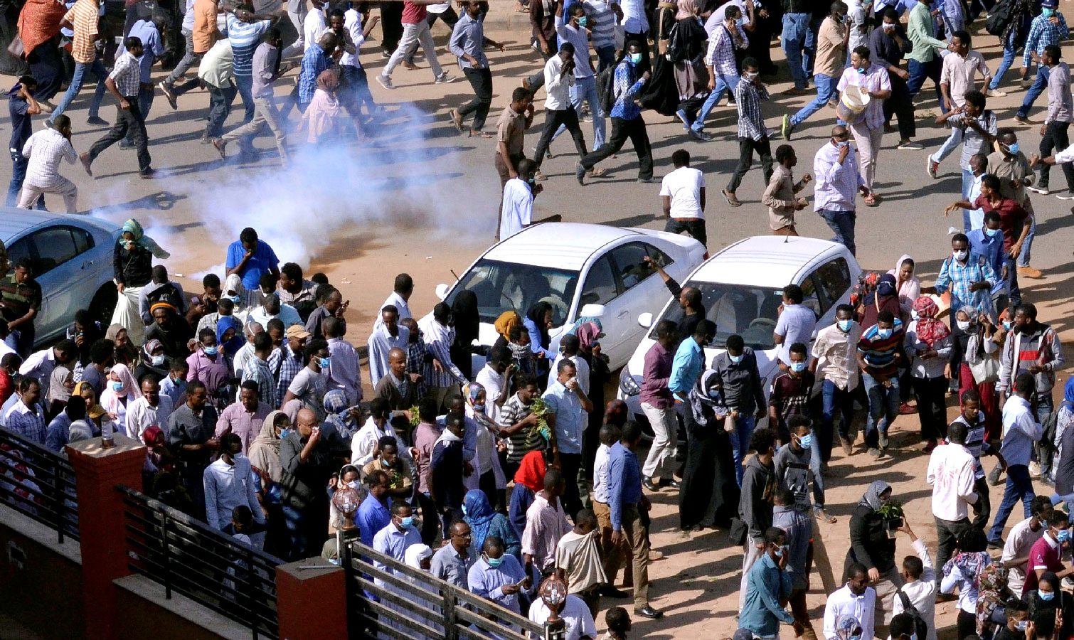 Sudanese demonstrators run from teargas lobbed to disperse them as they march along the street during anti-government protests in Khartoum, Sudan December 25, 2018. 