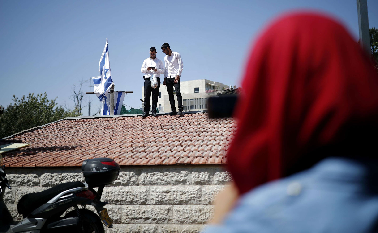 Religious Jewish men stand on the roof of a house seized by new Jewish owners in the Arab neighbourhood of Sheikh Jarrah in east Jerusalem on September 8, 2017, which originally belonged to the Palestinian Shamasneh family in which they lived for over half a century, until they were evicted on September 5.