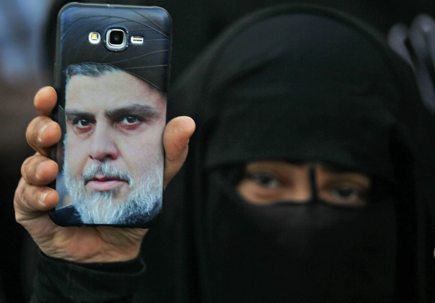 عراقية ترفع صورة مقتدى الصدر في تظاهرة احتجاج على الحكومة وسط بغداد