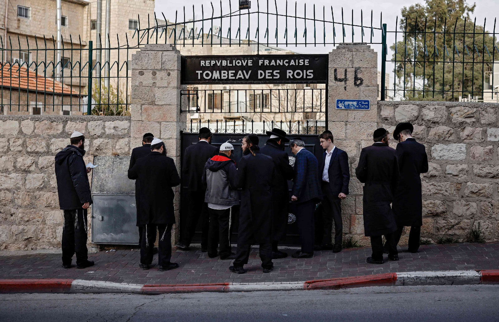 Jewish Ultra Orthodox men pray at the closed gate of the Tombs of the Kings, owned and administered by the French Consulate of Jerusalem, in east Jerusalem on January 24, 2019.