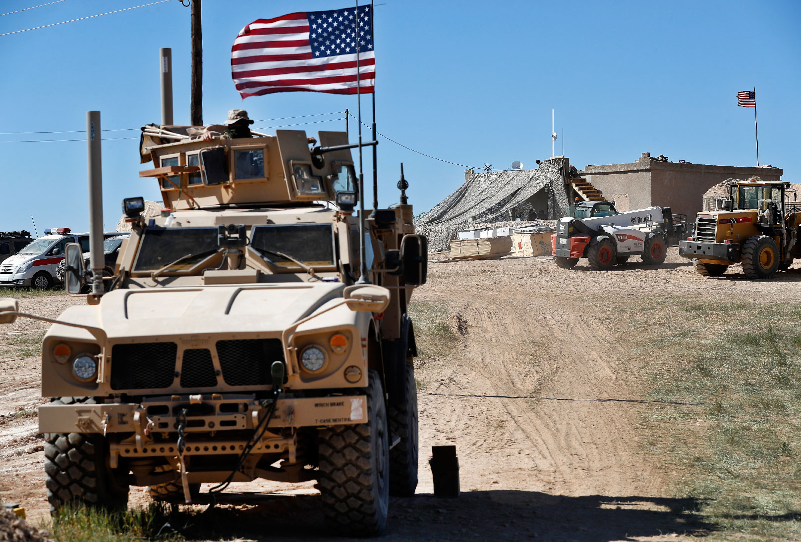 A US soldier, left, sits on an armored vehicle in Manbij, northern Syria.