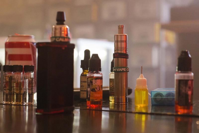 An assortment of e-liquids sit next to two portable vaporisers.