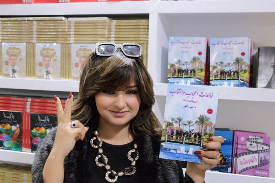 Dena Anwer holding her book "Those Taking Off the Hijab: The Silent Revolution"