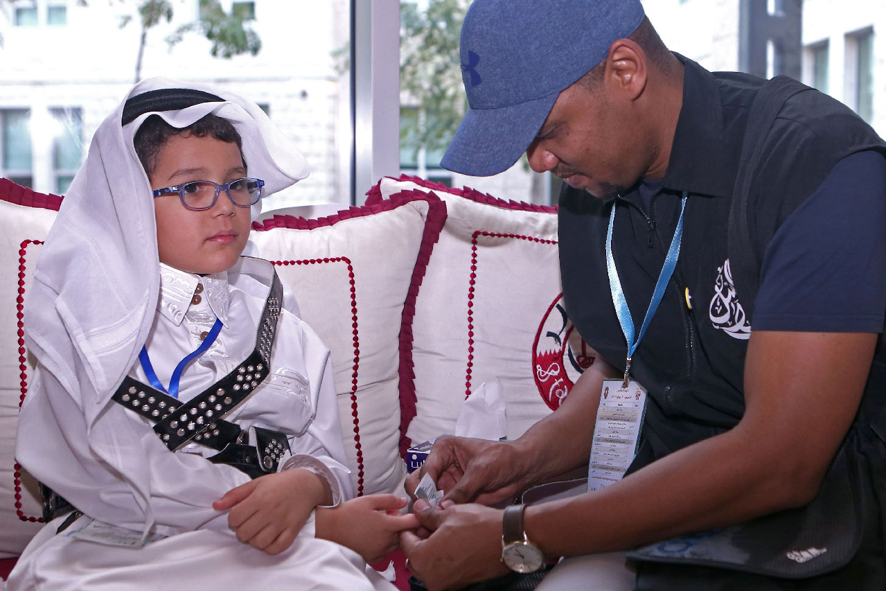 A man tests Qatari child Tamim Abdelmoniem Allafi's blood during the 19th International al-Bawasil Children with diabetes camp in Doha.