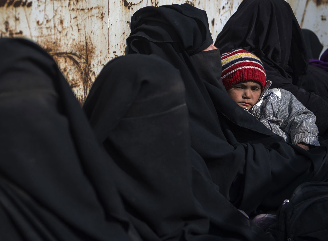 In this file photo taken on February 14, 2019 women and children who fled the Islamic State (IS) group's embattled holdout of Baghouz sit waiting in the back of a truck in the eastern Syrian province of Deir Ezzor.