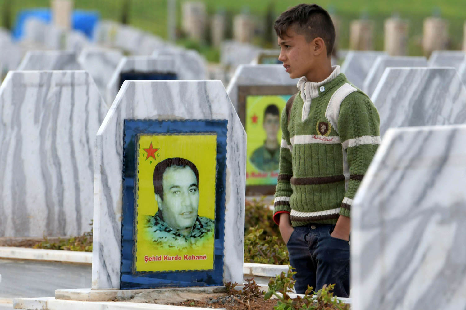 طفل يتجول بين قبور مقاتلين أكراد قضوا في الحرب ضد داعش