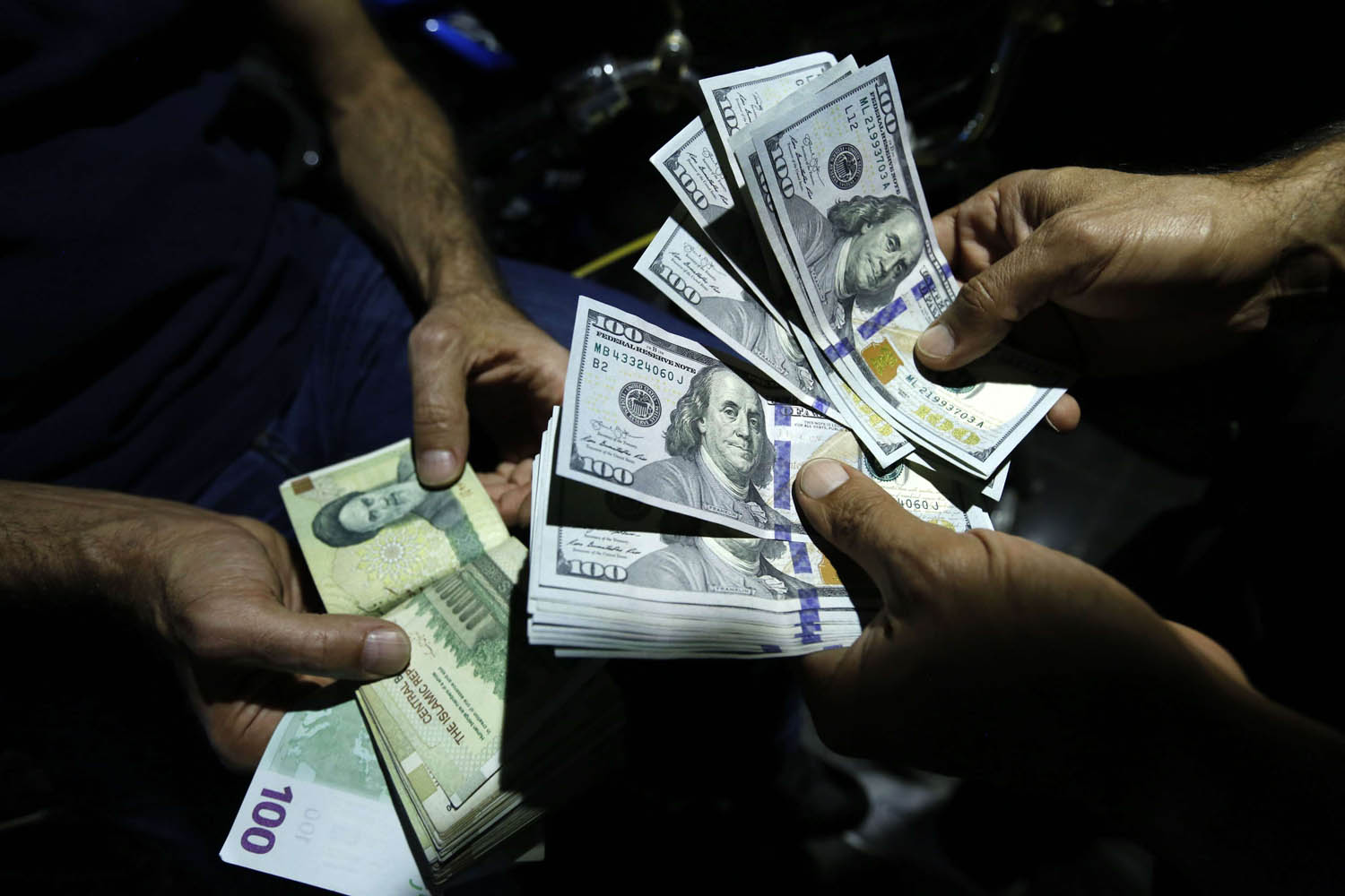 تجار عملة يتبادلون الدولار والتومان الإيراني