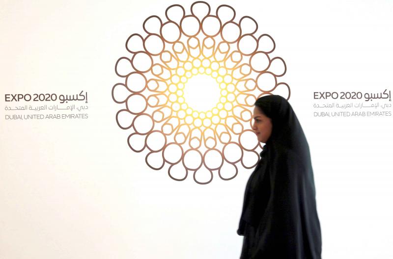 A woman walks past the logo of Expo 2020 in Dubai, United Arab Emirates