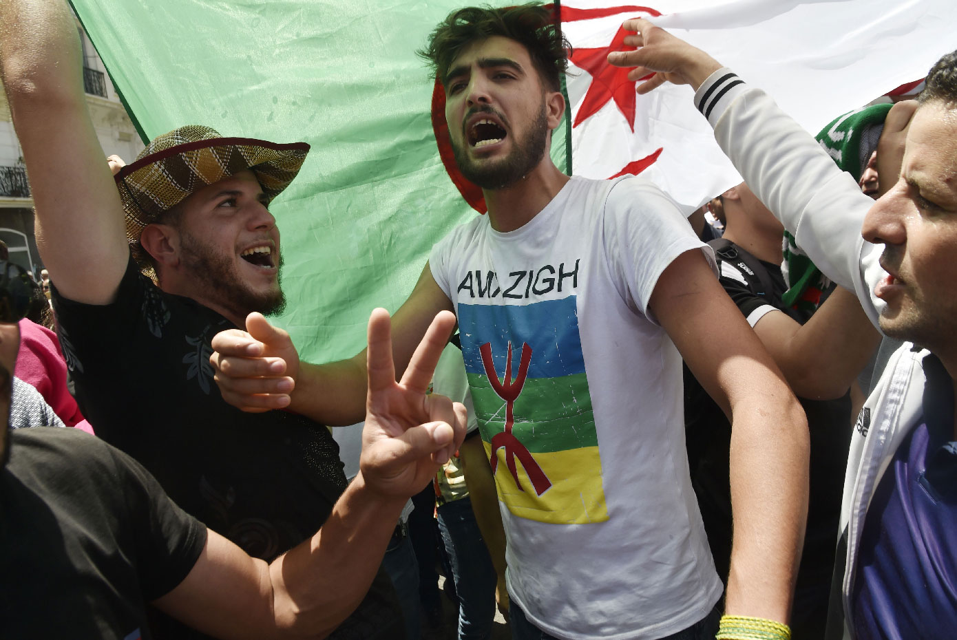 Algerian protesters shout anti-system slogans in front of a national flag during the weekly Friday demonstration in Algiers