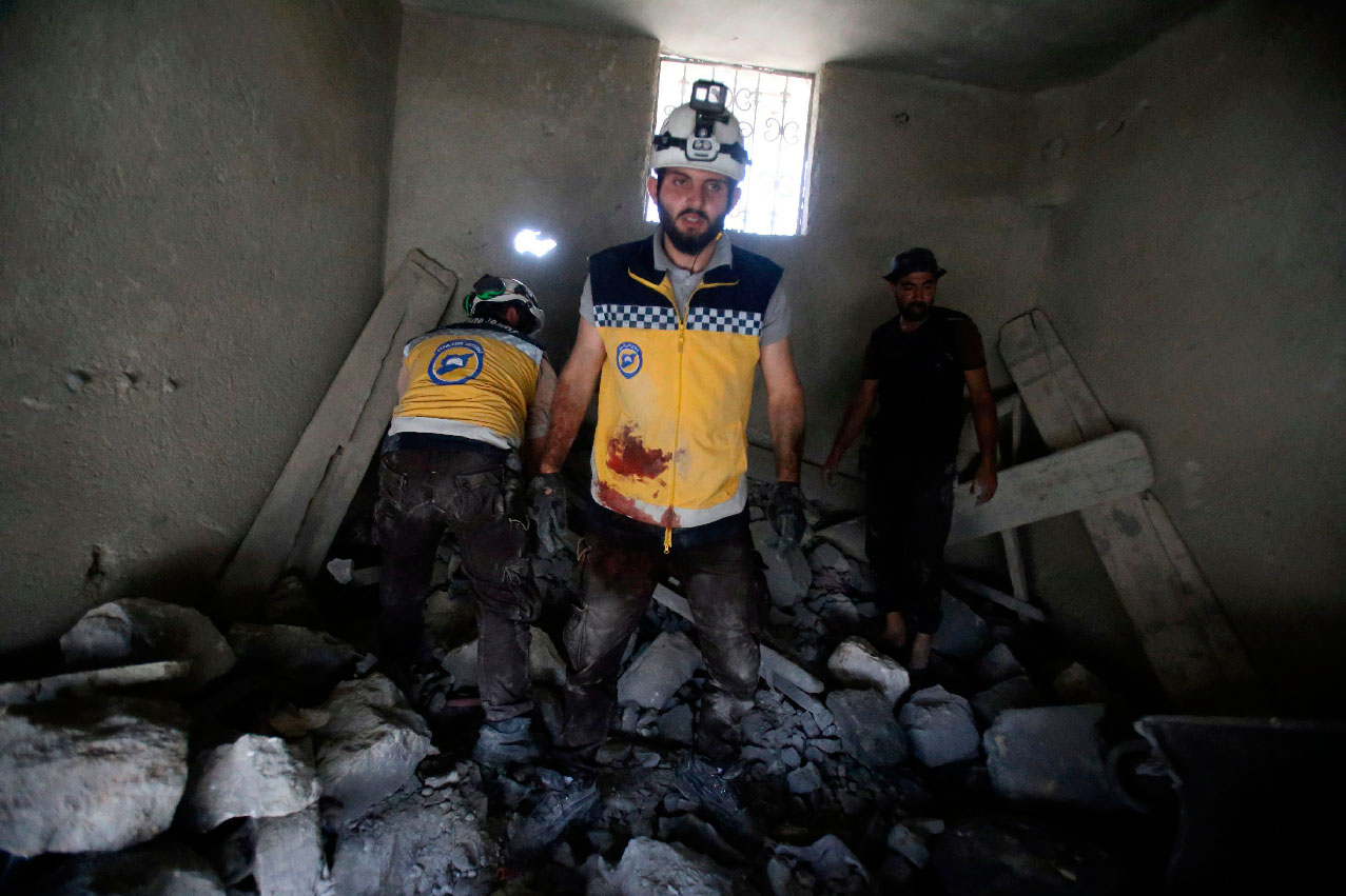 Members of the Syrian Civil Defence dig through the rubble of a building following reported airstrikes