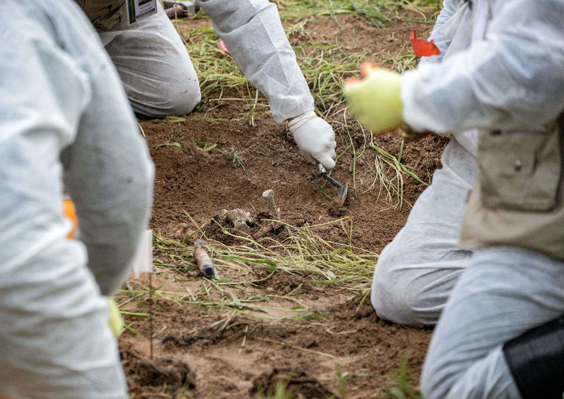 Forensic workers inspect a zone during the exhumation of a mass-grave of hundreds of Yazidis killed by Islamic State (IS) group militants in the northern Iraqi village of Kojo