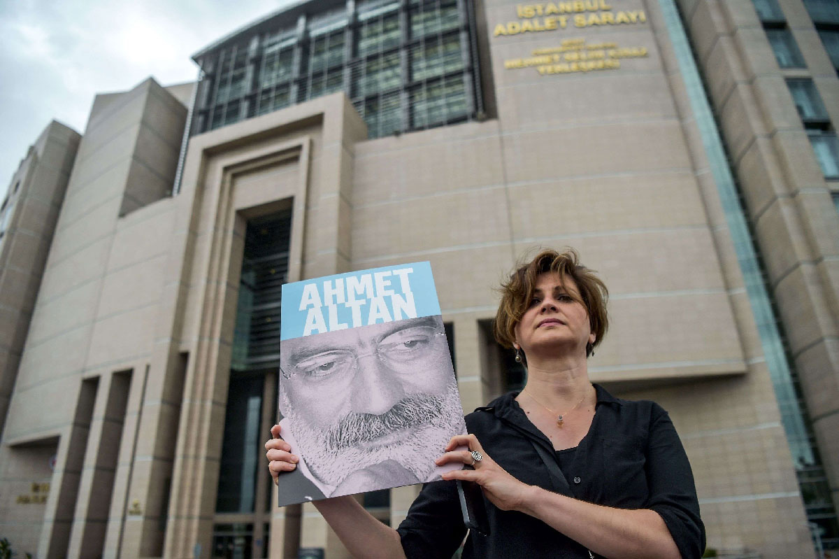 Journalist posing with a portrait of Turkish journalist Ahmet Altan in front of the Istanbul courthouse