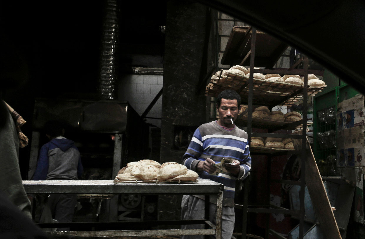 A vendor counts his money at a bread stand in the Sayeda Zeinab neighborhood of Cairo