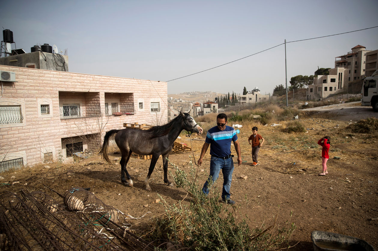 Ismail Obeideh walks with his horse near his home in the Palestinian village of Sur Baher