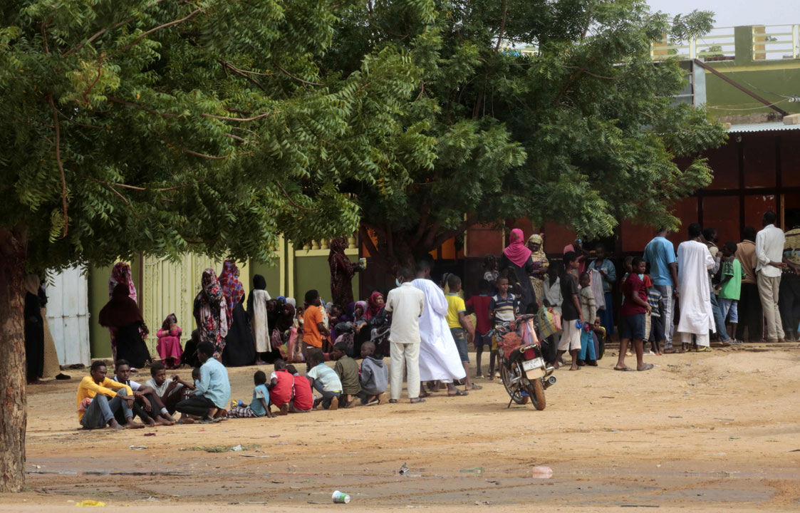 People stand in a queue outside a bakery in the central Sudanese city of Al-Obeid